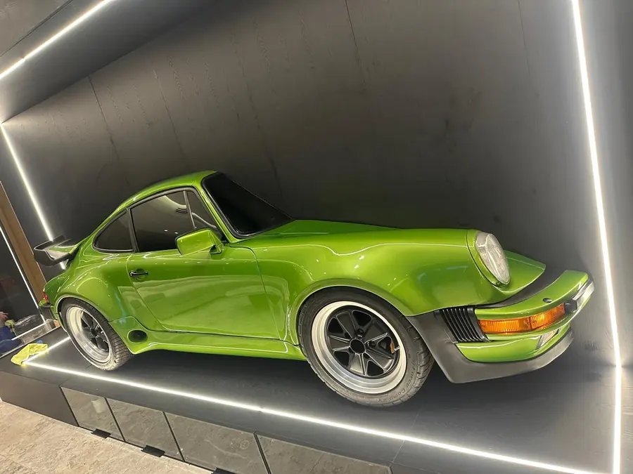 Porsche 911 verde visto de frente sobre el panel